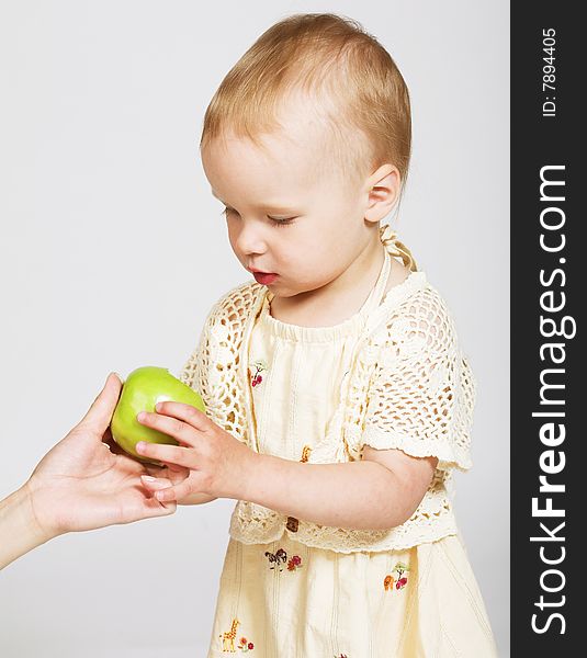 Studio portrait of a little girl taking an apple from the mother's hand. Studio portrait of a little girl taking an apple from the mother's hand