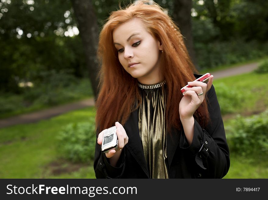 Young attractive girl talking on a phone while strolling in the park. Young attractive girl talking on a phone while strolling in the park.