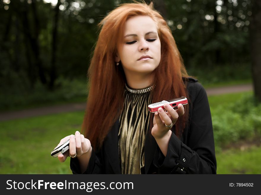 Young attractive girl talking on a phone while strolling in the park. Young attractive girl talking on a phone while strolling in the park.