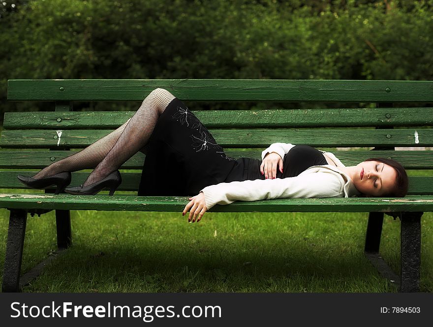 Portrait of a red-haired young woman relaxing on the bench in city-park