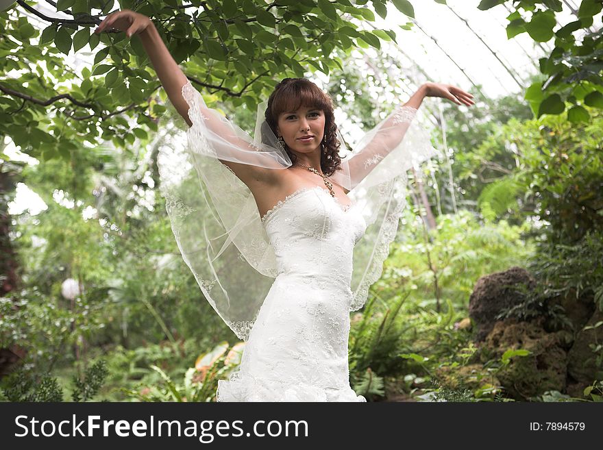 Lovely, happy bride walking in a park after marriage. Lovely, happy bride walking in a park after marriage.
