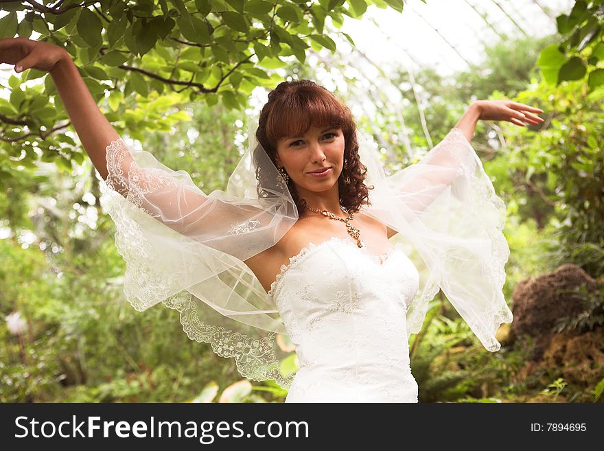 Lovely, happy bride walking in a park after marriage. Lovely, happy bride walking in a park after marriage.