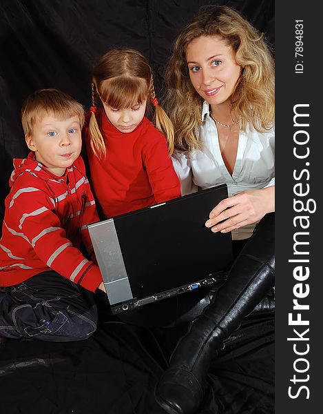 Young woman teaches two 4 year old kids with a laptop. Young woman teaches two 4 year old kids with a laptop