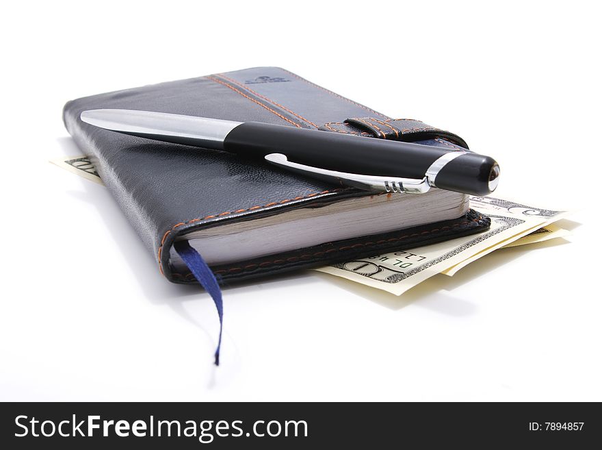 Leather notebook and pen lying on american dollars isolated on white