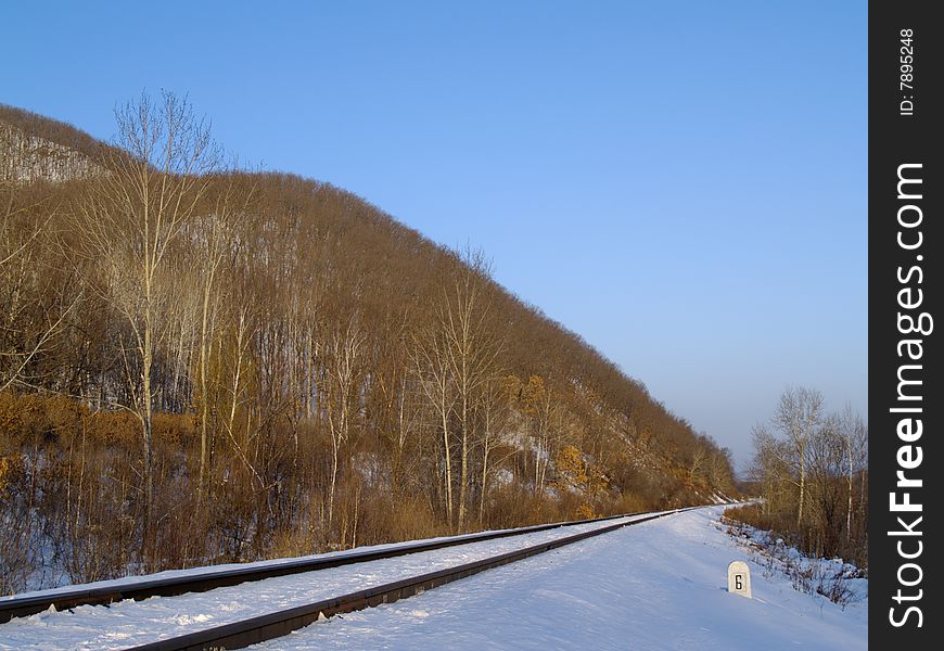 Winter landscape with railway rails at a mountain slope