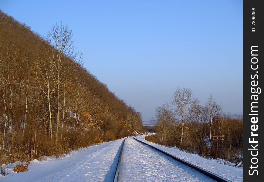 Winter landscape with railway rails at a mountain slope