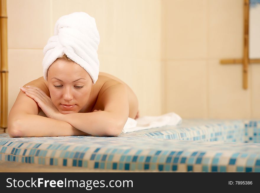 The girl in a towel lies on the brink of pool. The girl in a towel lies on the brink of pool