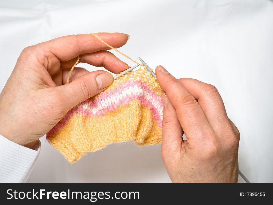 Two hands knitting a wool dress