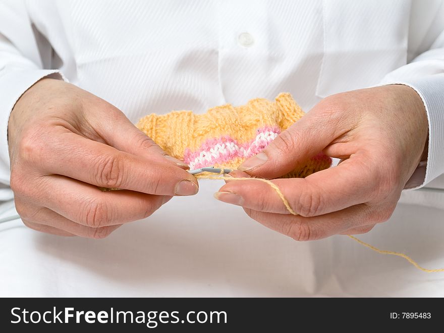 Two hands knitting a wool dress