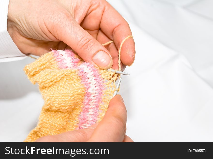 Two hands knitting a wool dress