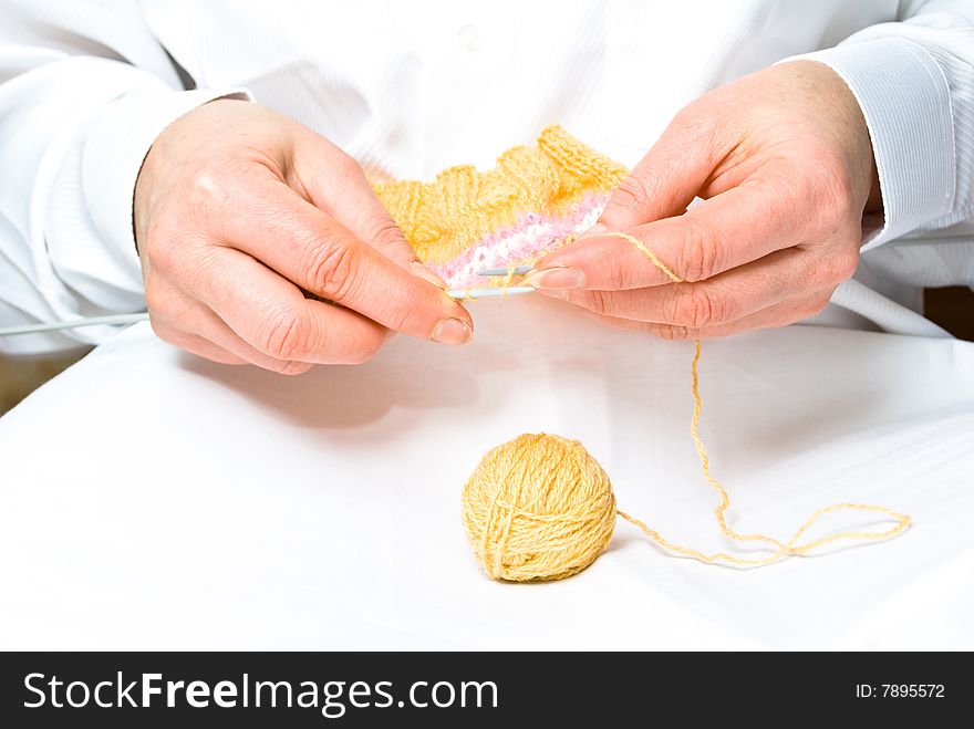 Two hands knitting a wool dress