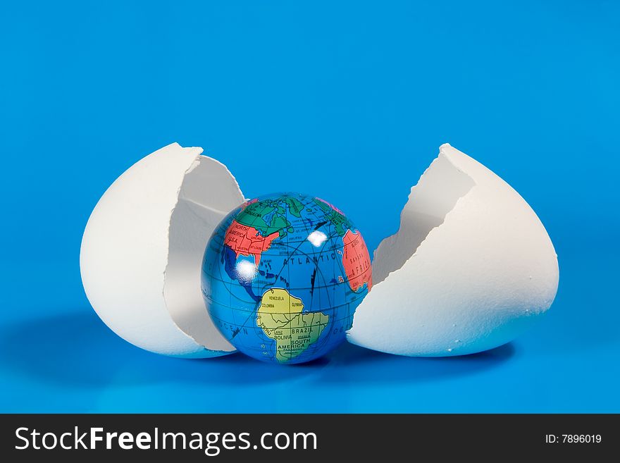 Small globe in broken eggshell (on a blue background)