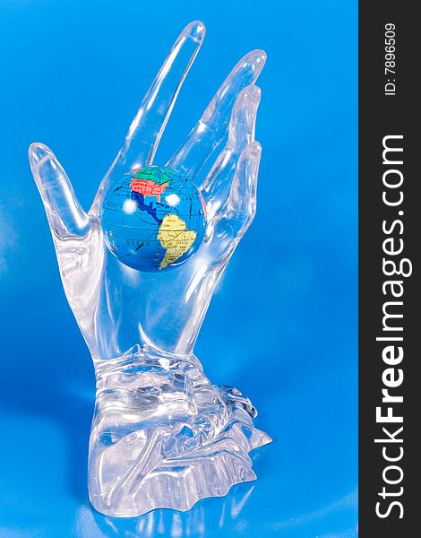 Small globe in a glass hand (on a bright blue background)