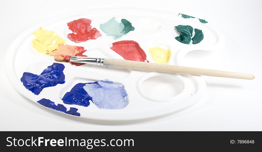 White palette with mixed paints and paintbrush. White palette with mixed paints and paintbrush