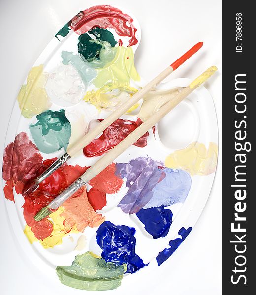 White palette with mixed paints and paintbrushes. White palette with mixed paints and paintbrushes