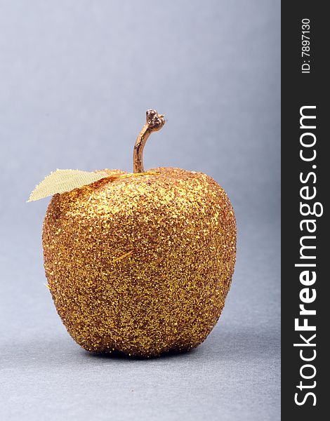 A golden apple is on gray background