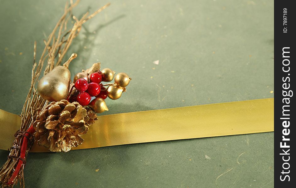 Christmas decoration and a golden ribbon on a green wrapping with copy space. Christmas decoration and a golden ribbon on a green wrapping with copy space