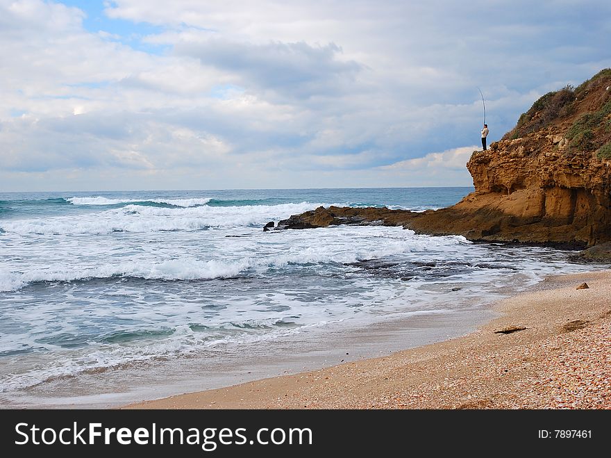 Fisherman on a rock on the shores of the Mediterranean Sea early in the morning