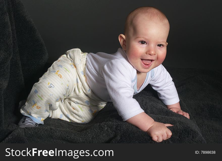 Laughing baby boy on a grey carpet