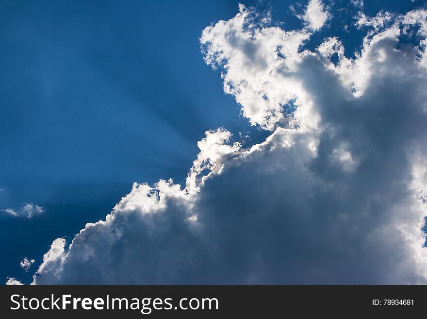 Sun's rays behind the cloud on bright blue sky. Sun's rays behind the cloud on bright blue sky