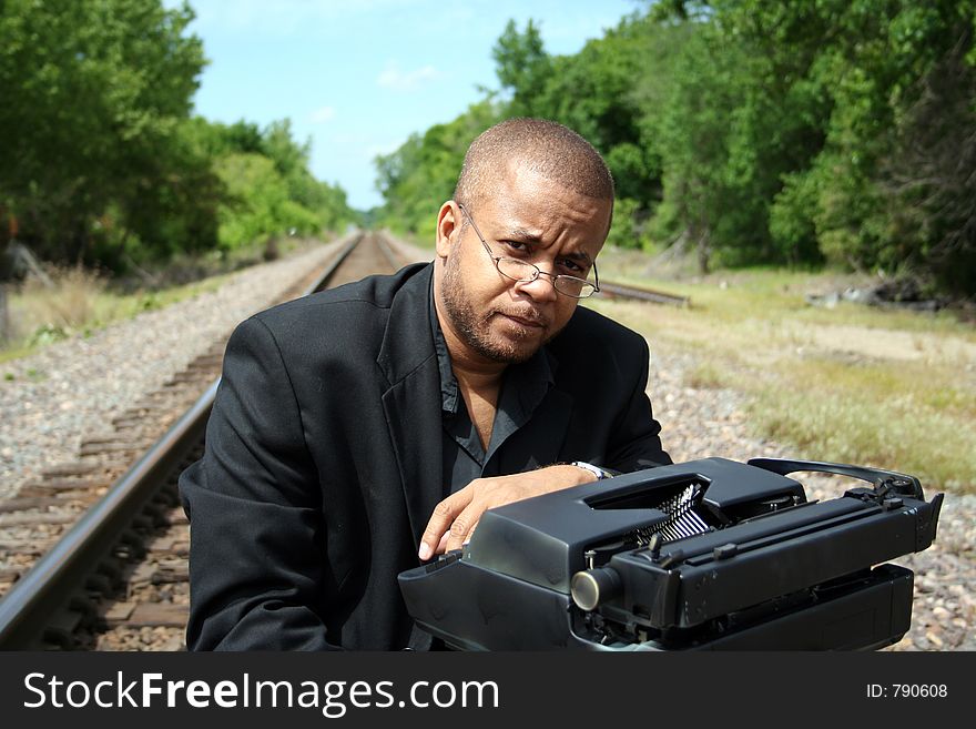 Young man with his typewriter on the train tracks. Young man with his typewriter on the train tracks.