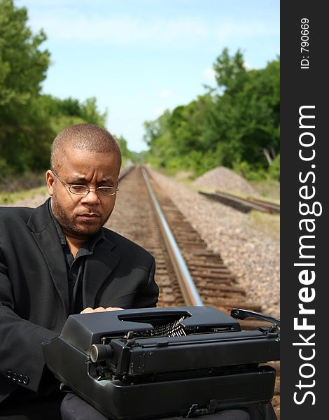 Young man with his typewriter on the train tracks. Young man with his typewriter on the train tracks.
