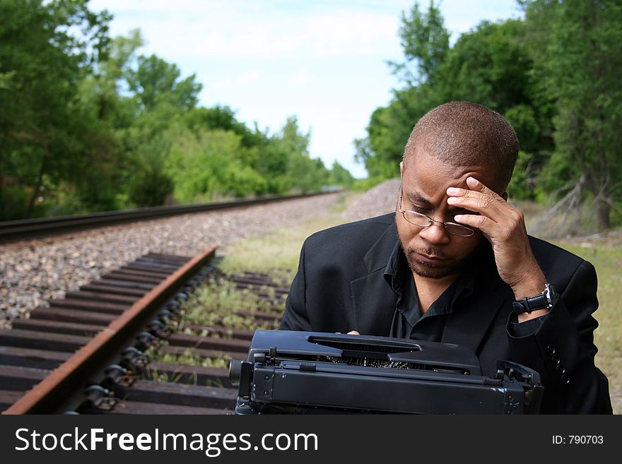 Young man with his typewriter on the train tracks. Young man with his typewriter on the train tracks.