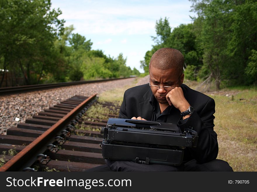 Young man with his typewriter on the train tracks. Young man with his typewriter on the train tracks.