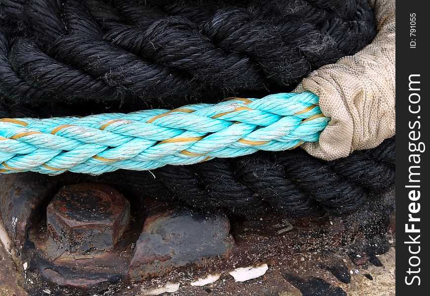 Detail in the harbour : blue anf black rope fastening a boat. Detail in the harbour : blue anf black rope fastening a boat