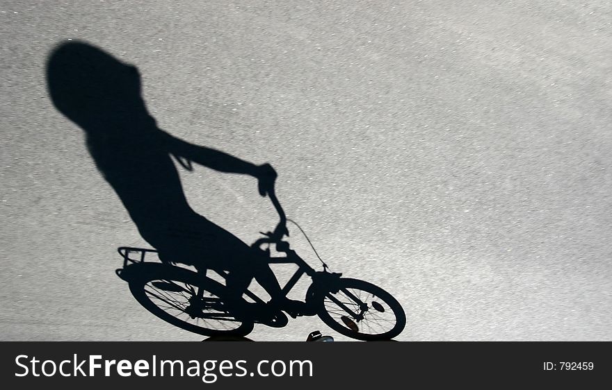 Shade on the road of a child on a bicycle. Shade on the road of a child on a bicycle