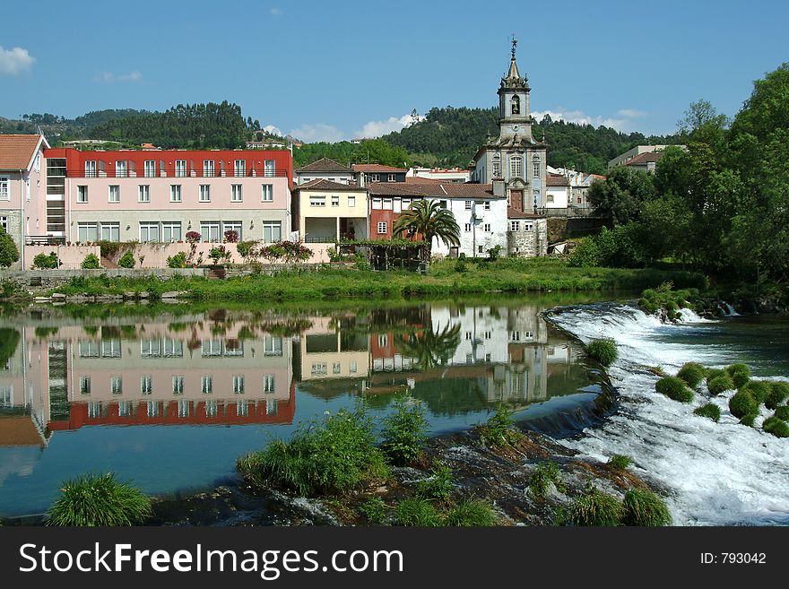 Village reflected in the river with cascade