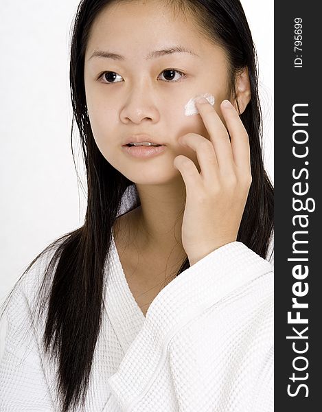A young chinese woman applying face cream
