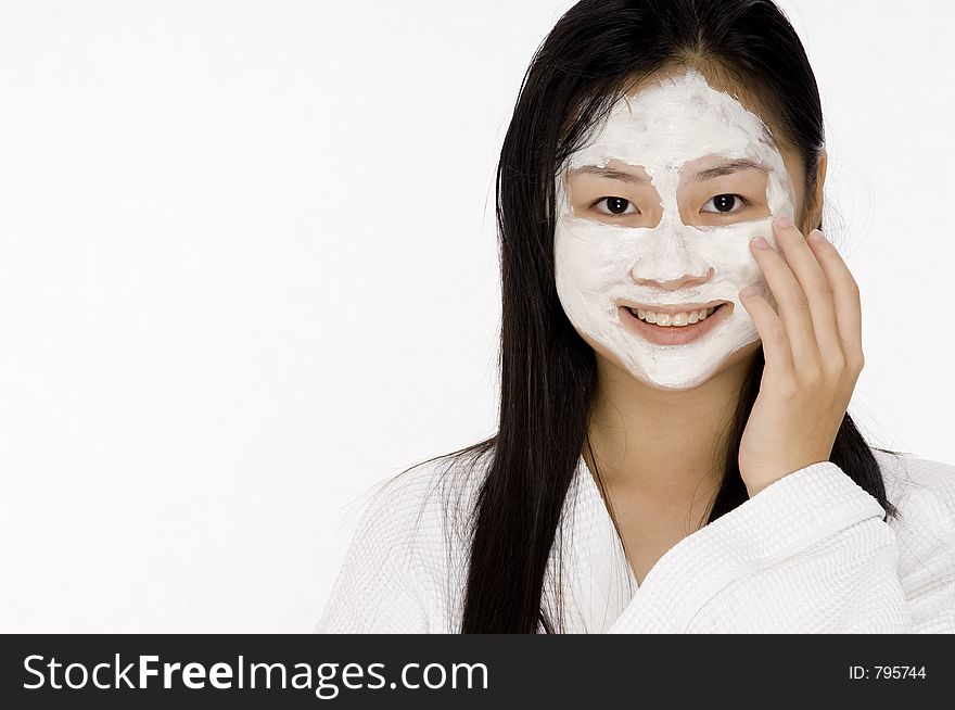 A young asian woman in a bath robe with a face pack on. A young asian woman in a bath robe with a face pack on