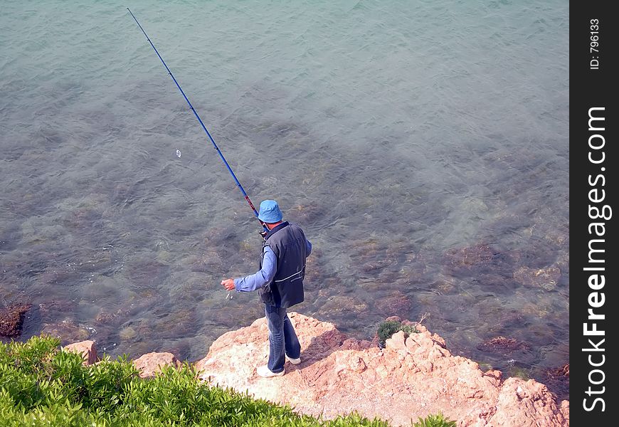 Alone man in blue with a fishing cane. Alone man in blue with a fishing cane