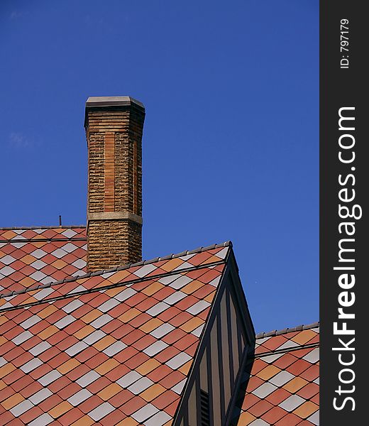 Colorful pink and red tile shingles on the roof of a building, with chimney on left. Colorful pink and red tile shingles on the roof of a building, with chimney on left.