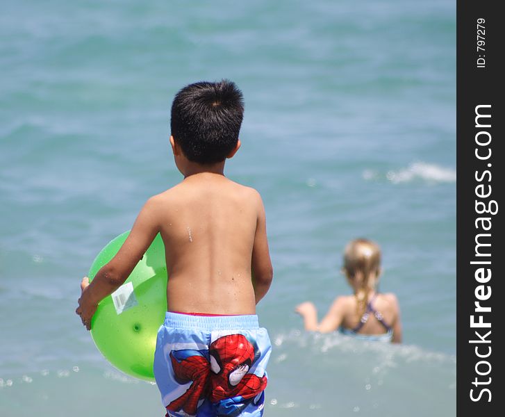 Boy on a beach running into the water with a ball. Boy on a beach running into the water with a ball