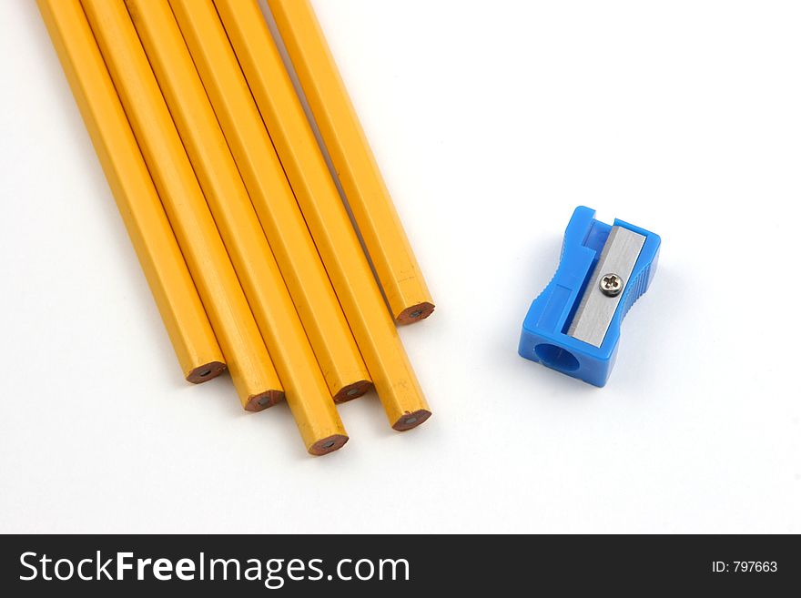 Group of pencils and a sharpener over a white background depicting the situation of sharpening pencils. Group of pencils and a sharpener over a white background depicting the situation of sharpening pencils