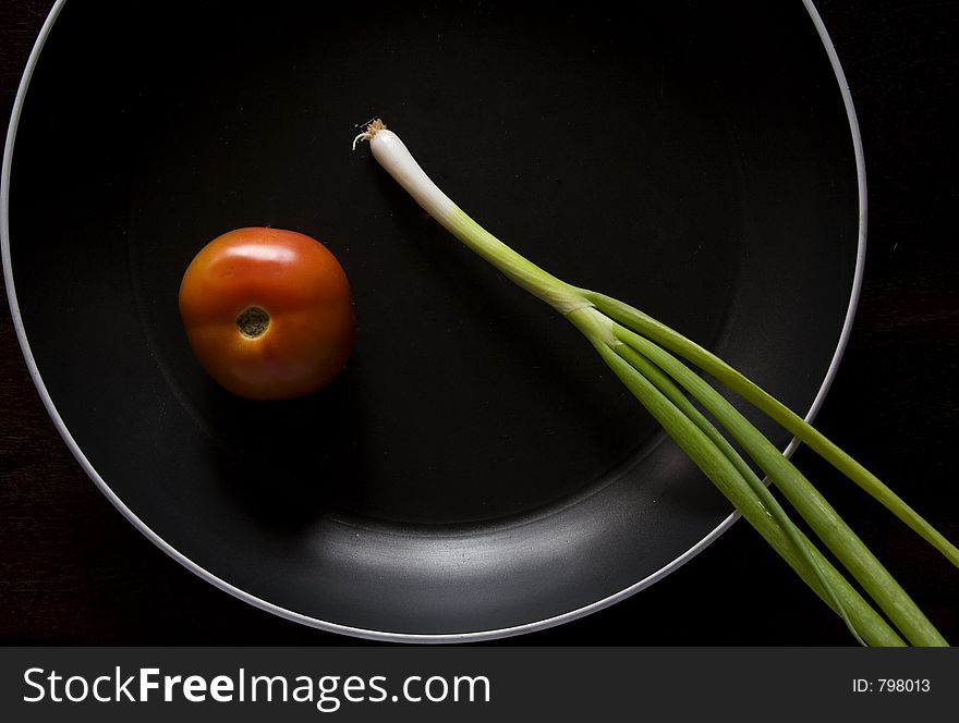 Tomato and spring onion in black non-stick pan. Tomato and spring onion in black non-stick pan