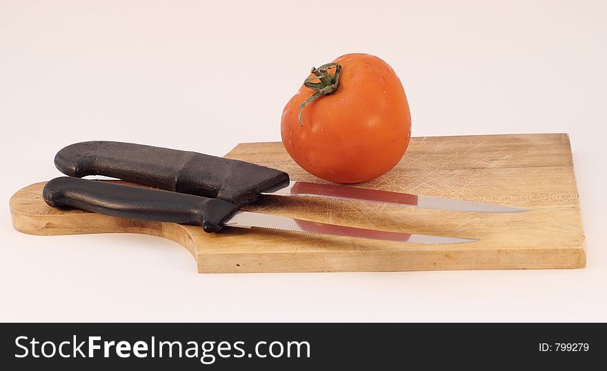 Tomato with a knife on a plate, isolated