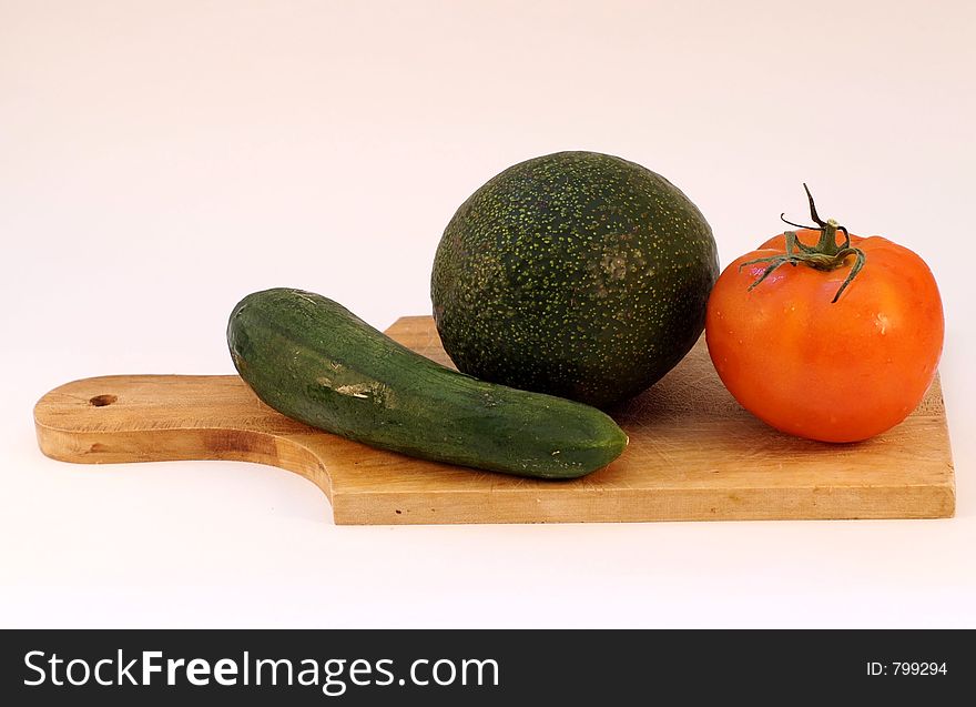 Cucumber, avocado, tomato on a wooden plate. Cucumber, avocado, tomato on a wooden plate