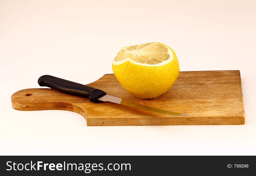 Lemon and a knife on a cooking wooden plate