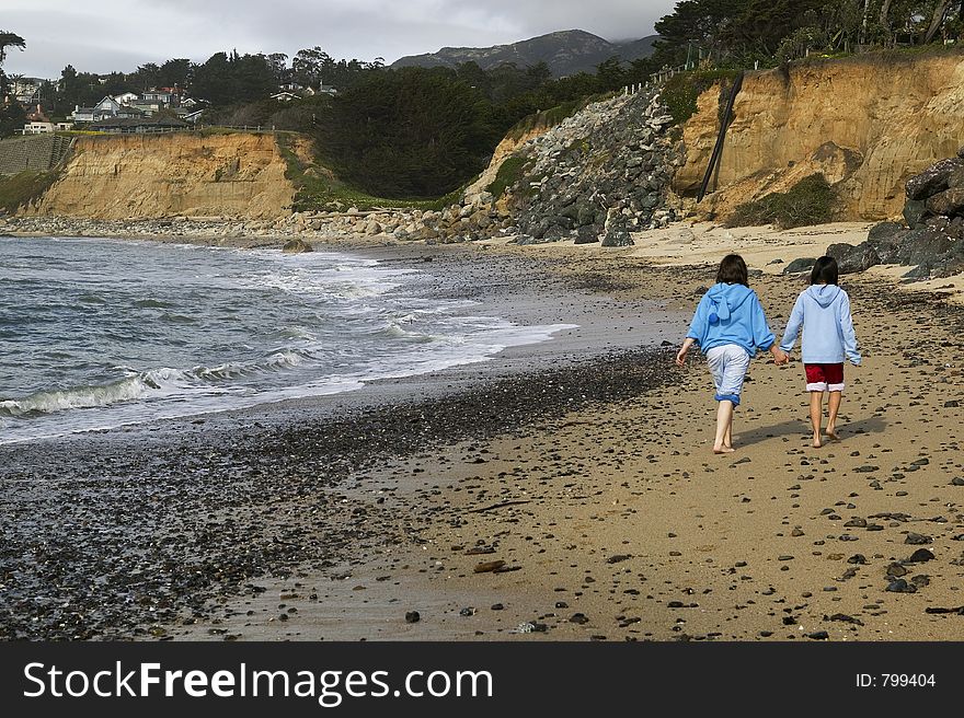 Two young girls walk down the beach.  High Res. Two young girls walk down the beach.  High Res