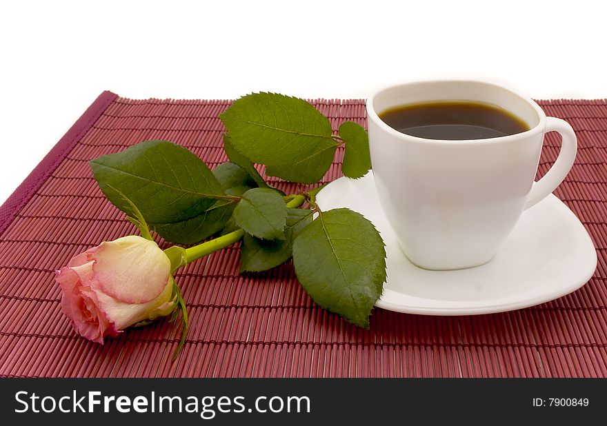 White cup of coffee and rose which lies on a table