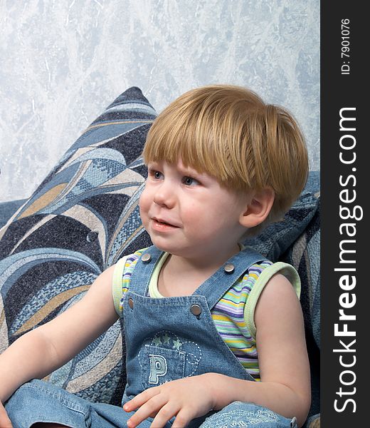 The little boy sits on a sofa expressing emotion. The little boy sits on a sofa expressing emotion