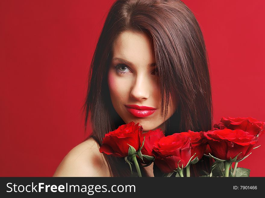 Close-up studio portrait of a beautiful woman with red rose, shoot on red background