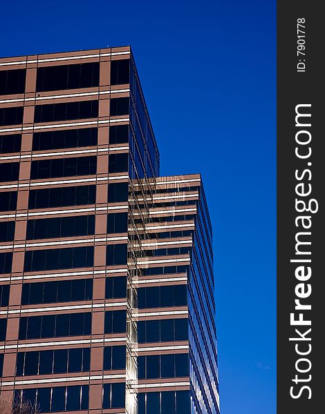 A modern brown glass office building against blue sky. A modern brown glass office building against blue sky