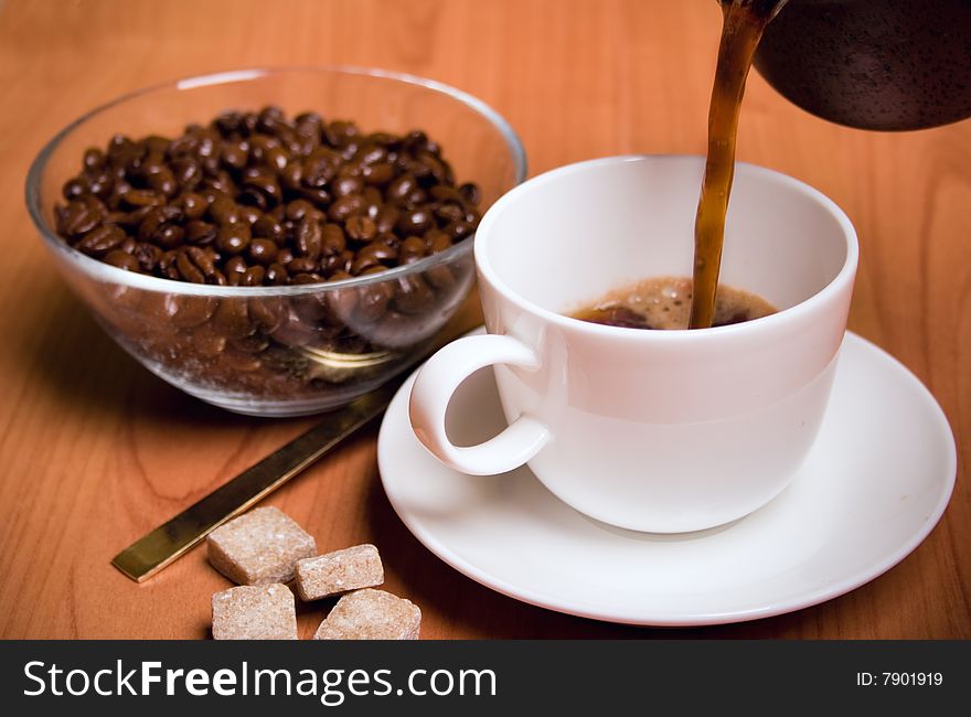 Cup of coffee, sugar and beans in glass bowl on wooden table