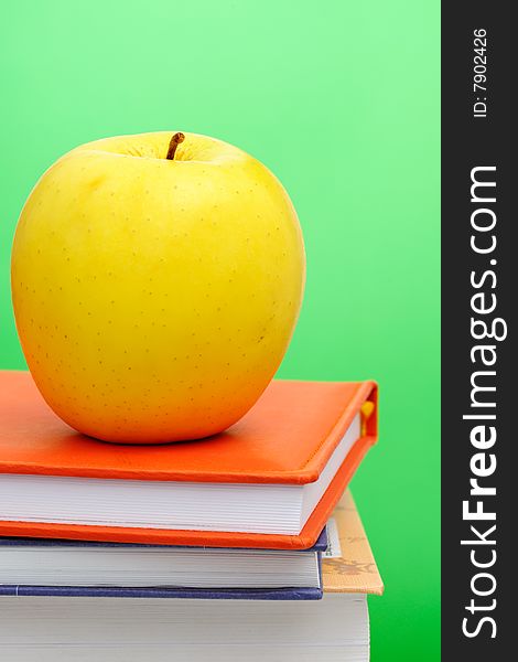 Yellow apple on stack of books against green background. Yellow apple on stack of books against green background.