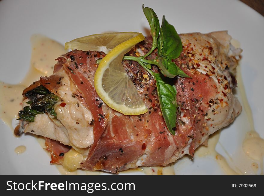 Chicken roll filled with asparagus spears, wrapped in prosciutto, topped with fresh lemon and basil.