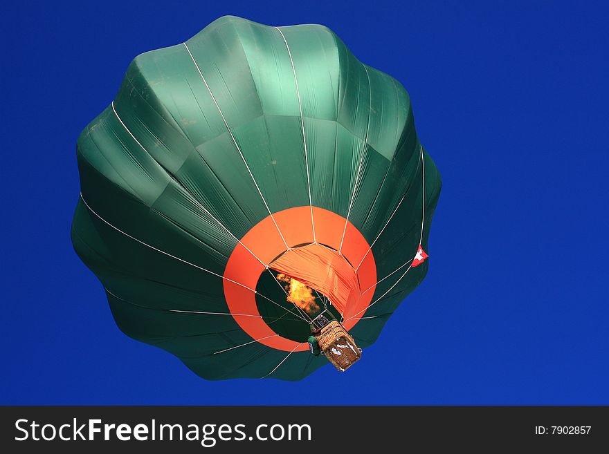 Dark green balloon designed for fast manuvering taking off from the launch side of Chateau d'Oex International Festival of Hot-Air Balloons 2009. The heating flame is visible. Balloon registration numbers have been digitally removed. Dark green balloon designed for fast manuvering taking off from the launch side of Chateau d'Oex International Festival of Hot-Air Balloons 2009. The heating flame is visible. Balloon registration numbers have been digitally removed.